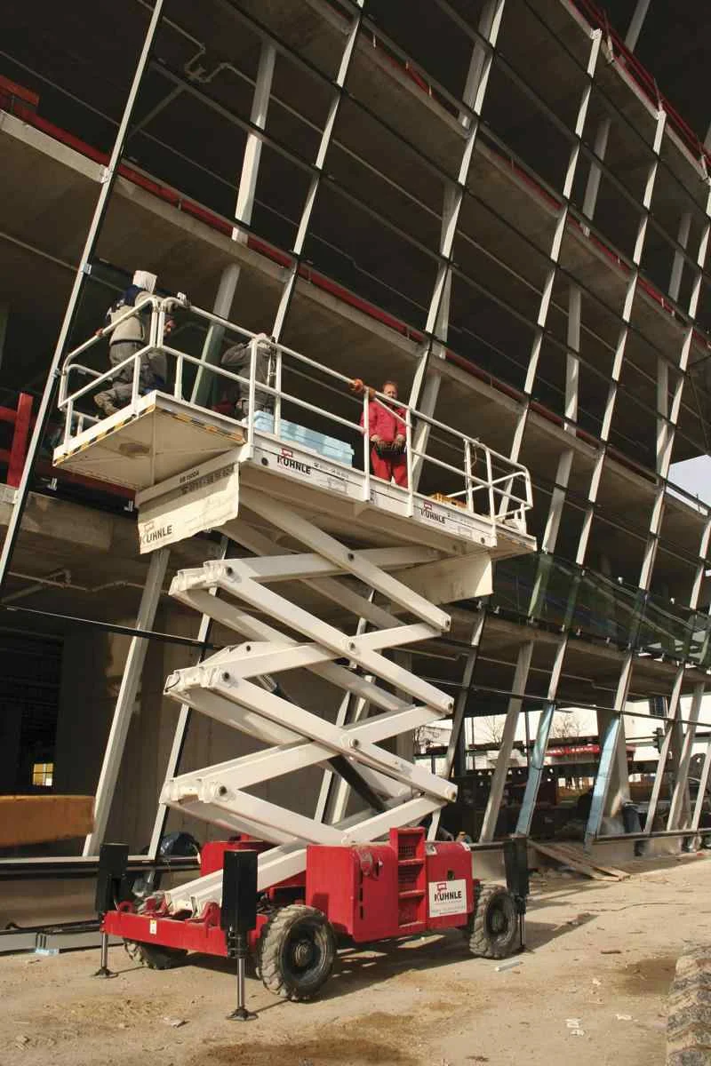 Leicht ausgefahrene Arbeitsbühne vor unfertigem Gebäude.