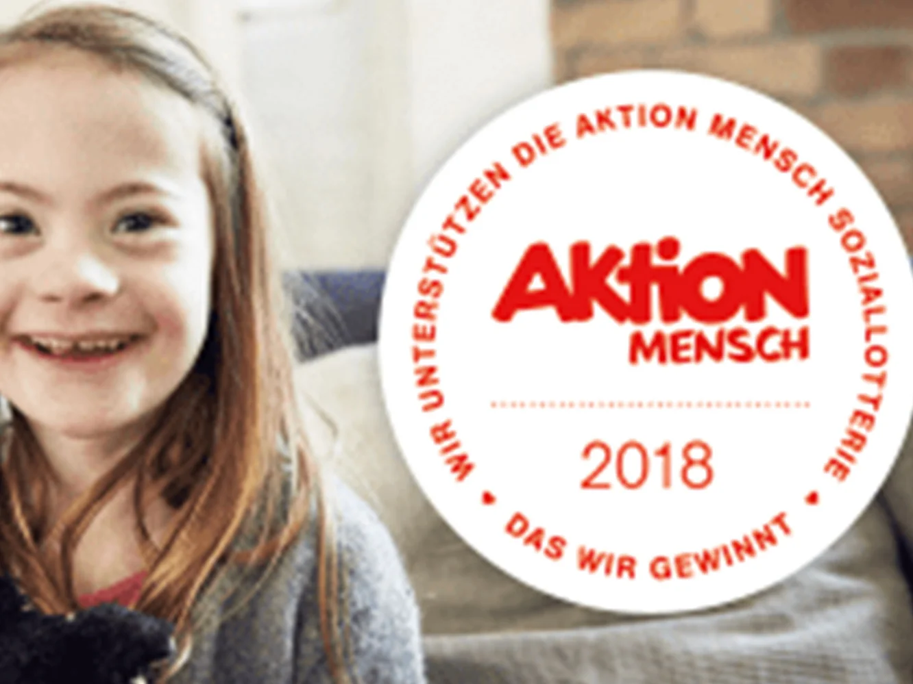 Mädchen und Aktion Mensch Logo vor Sofa.