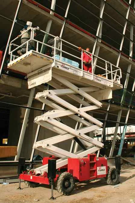 Leicht ausgefahrene Arbeitsbühne vor unfertigem Gebäude.