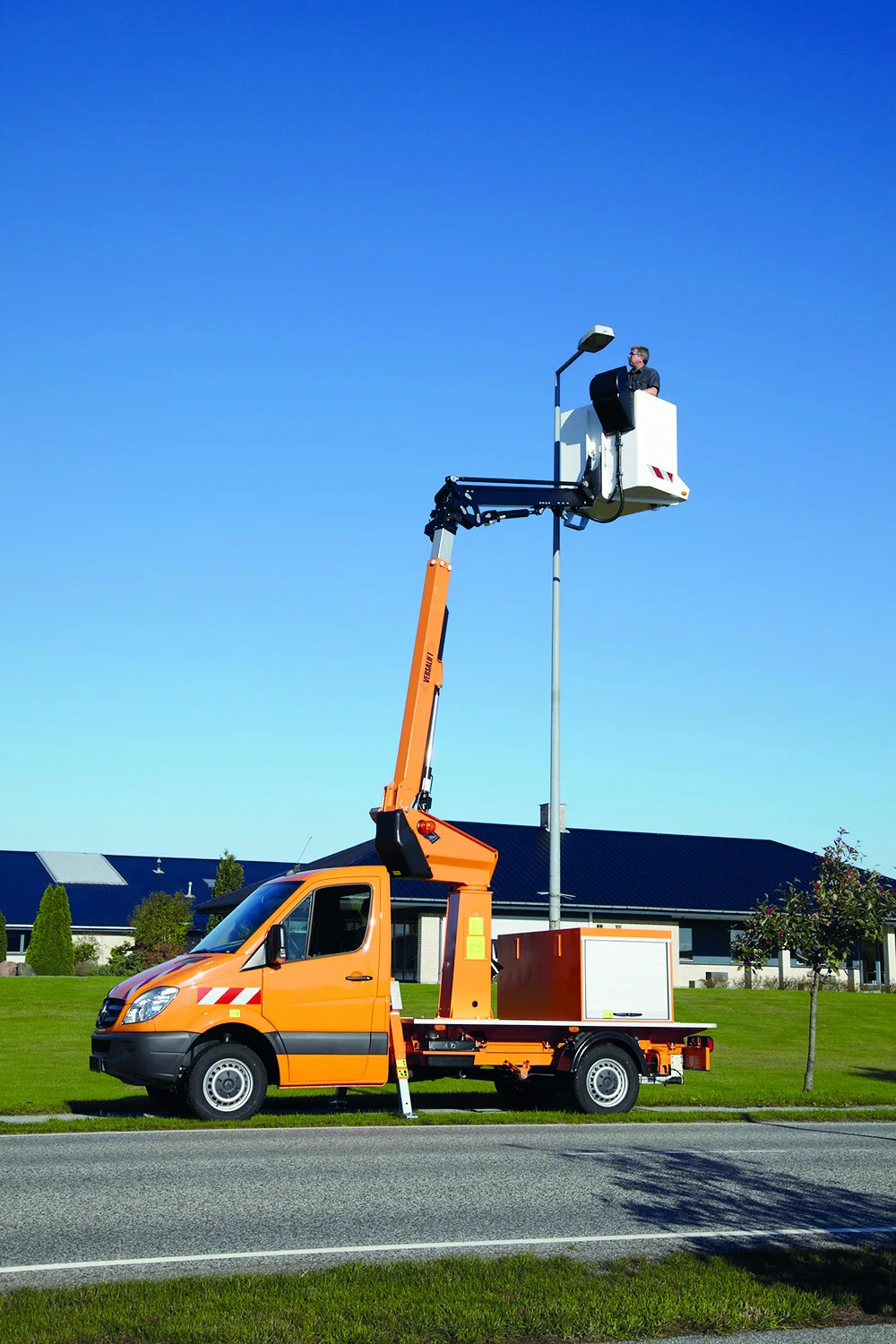 Seitliche Ansicht einer ausgefahrenen gelben Arbeitsbühne vor blauem Himmel.
