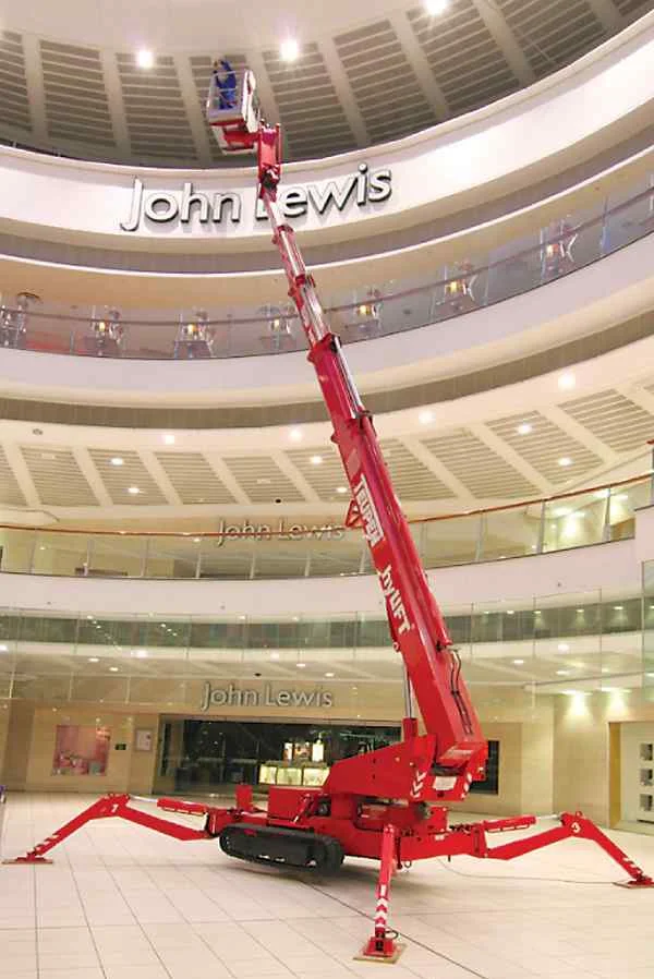 Rote ausgefahrene Arbeitsbühne in heller Halle.